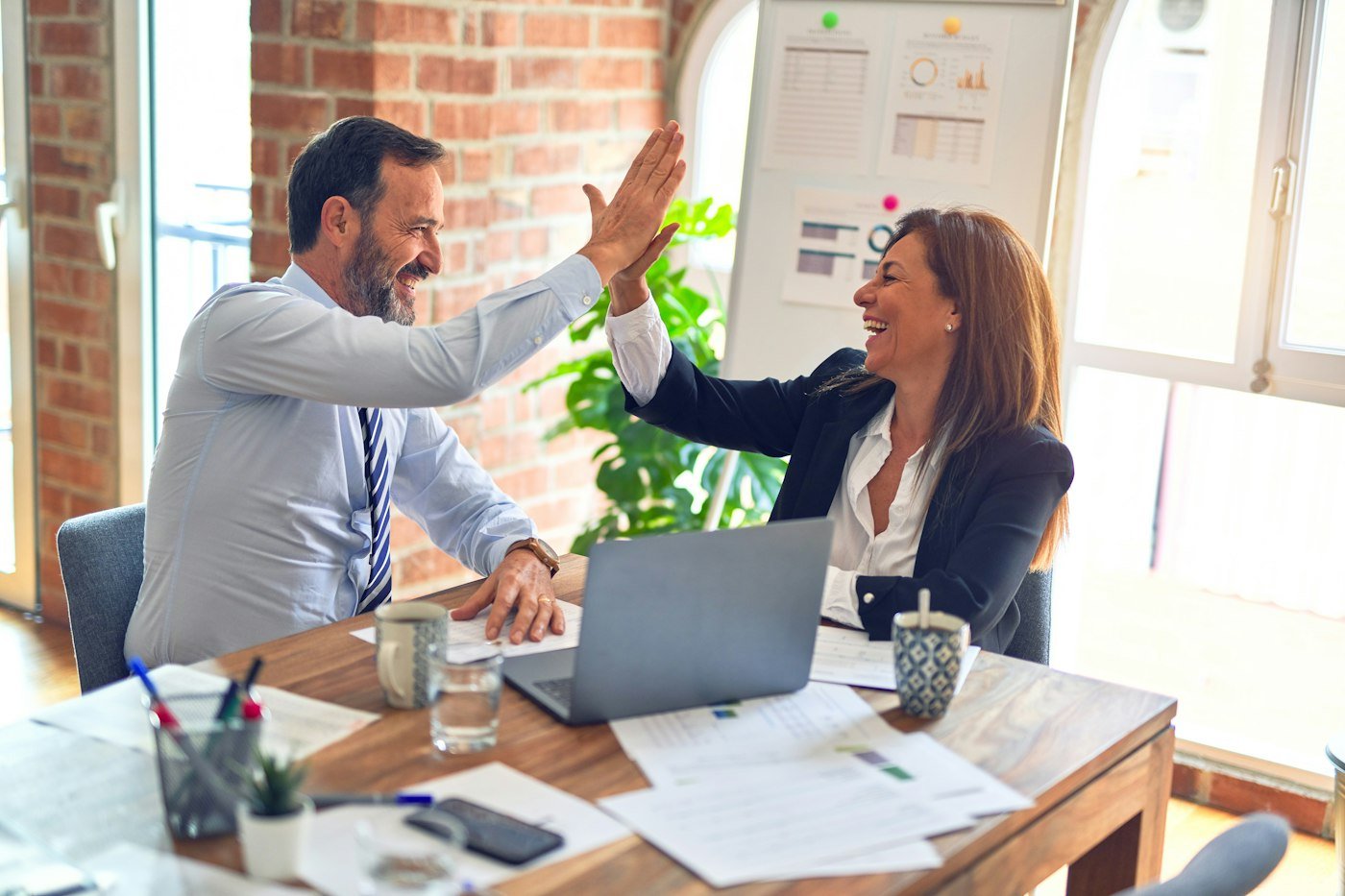 Two colleagues celebrating with a high five at a meeting table